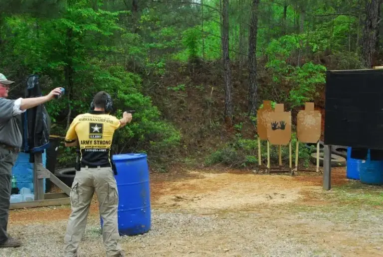 An IDPA competitor shooting from a blue barrel