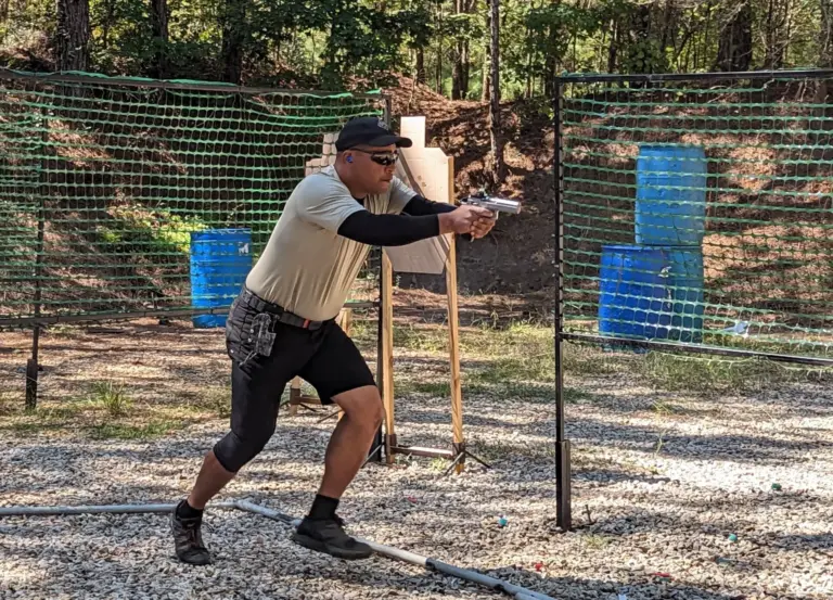An IDPA competitor shooting a stage between blue barrels in a pistol bay