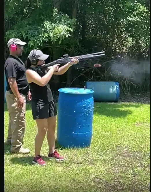 A shooter firing a shotgun on the range